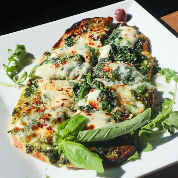 Bacco Bistro's Italian flatbread, topped with melted cheese, spinach, red pepper flakes, and fresh basil.